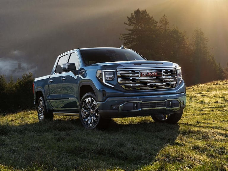A Blue GMC Sierra 1500 Parked on a Hill as the Sun Shines Down on the Pickup Truck