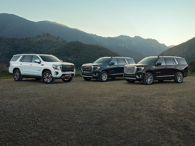 A Lineup of the 2024 GMC Yukon Trims Parked in front of a mountain range
