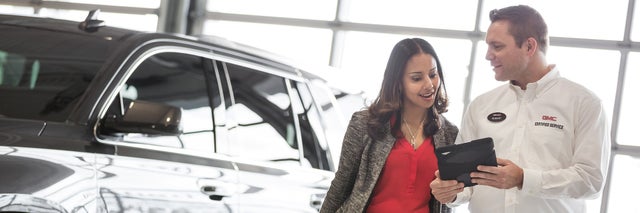 GMC Service Advisor speaking with customer next to vehicle